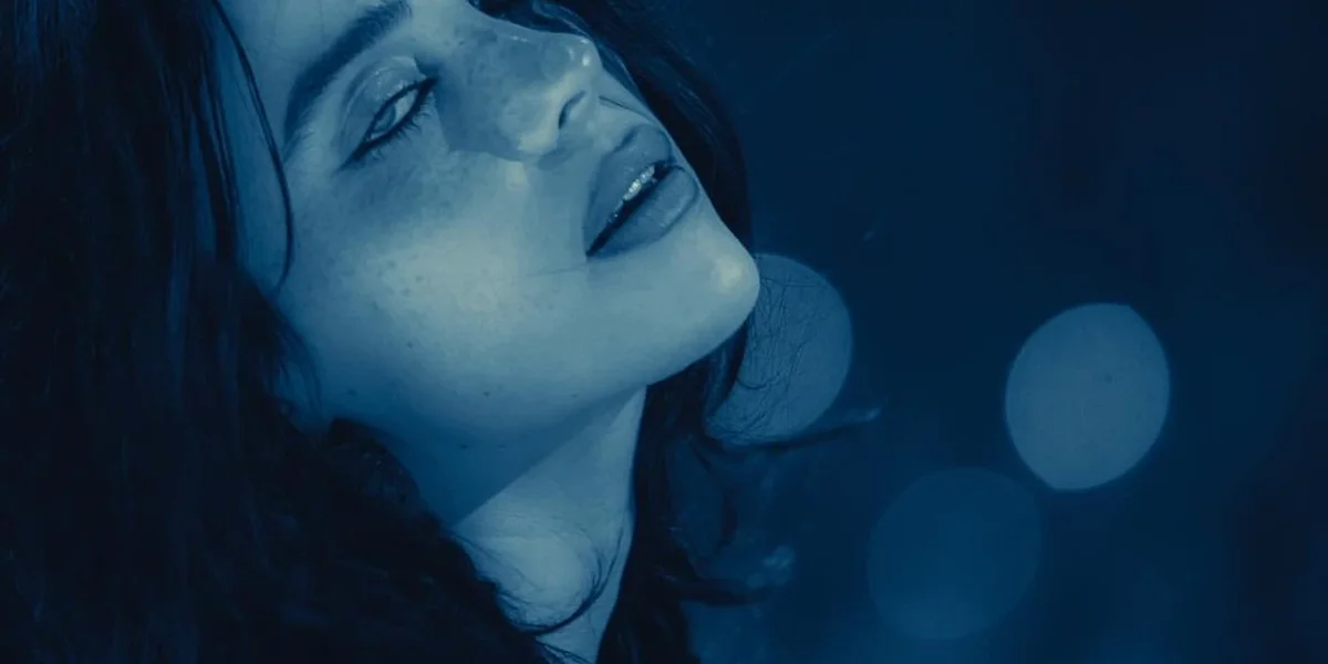 Billie Eilish performing under soft blue lighting during an emotional live performance